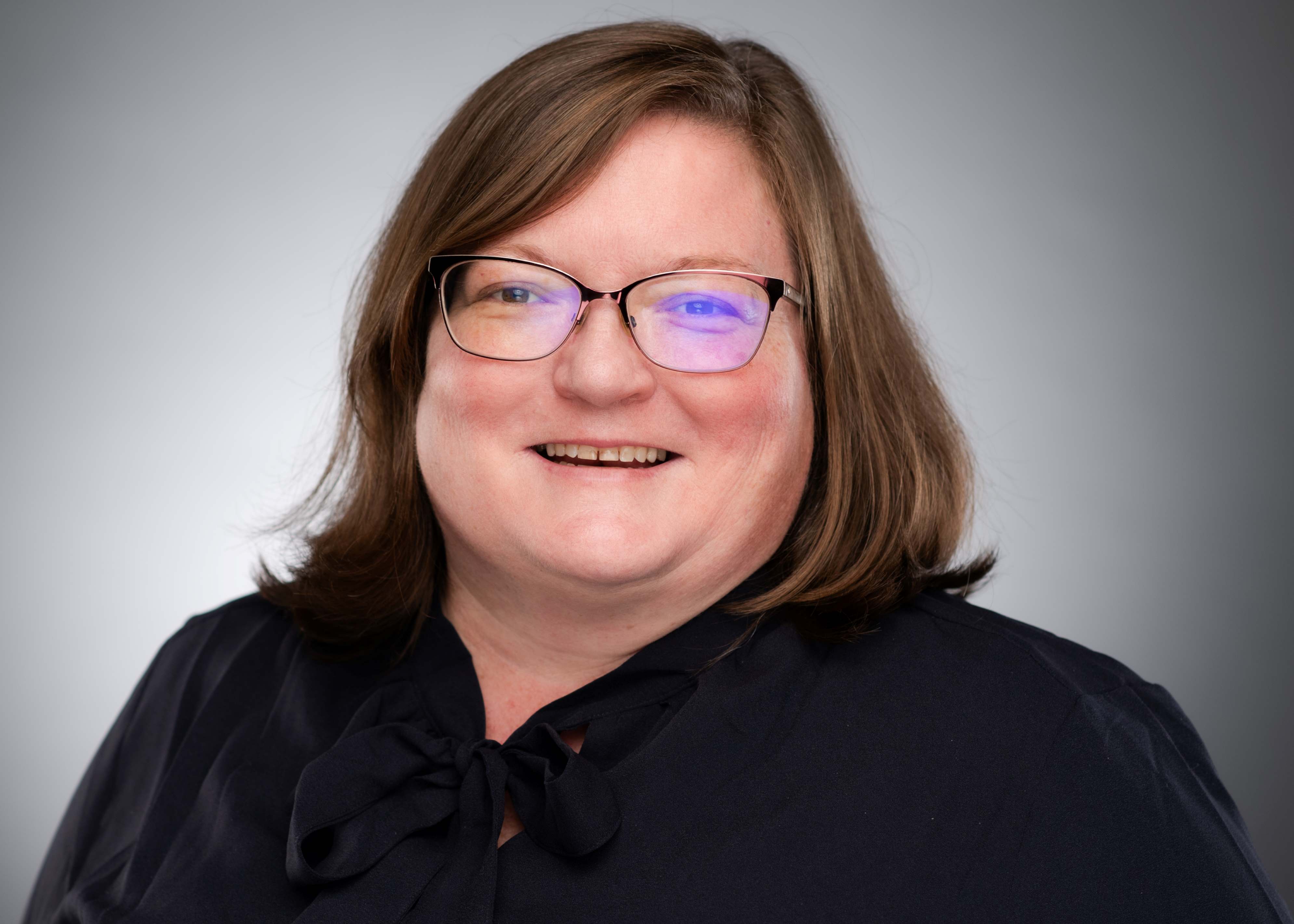 Picture of Annie Butler wearing navy blouse and glasses.